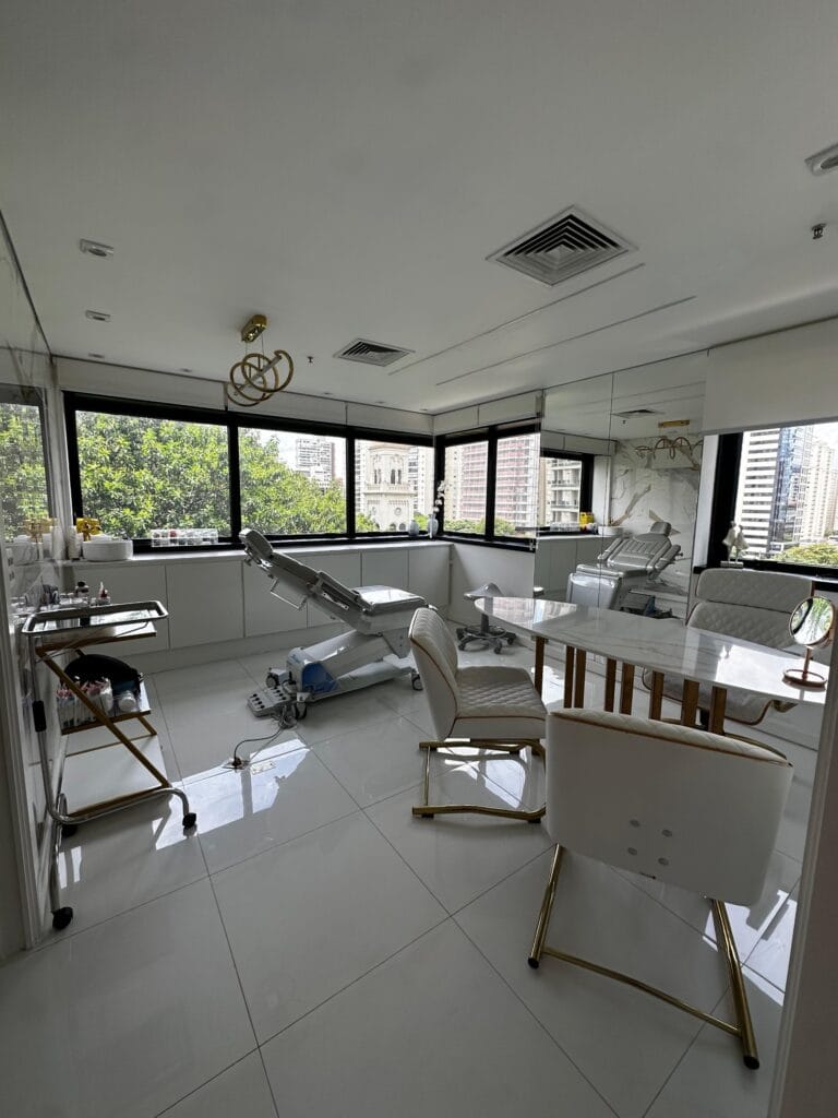 Sala de atendimento do consultório de dermatologia da Dra. Thais Akemi em Moema, com maca e mesa de consulta