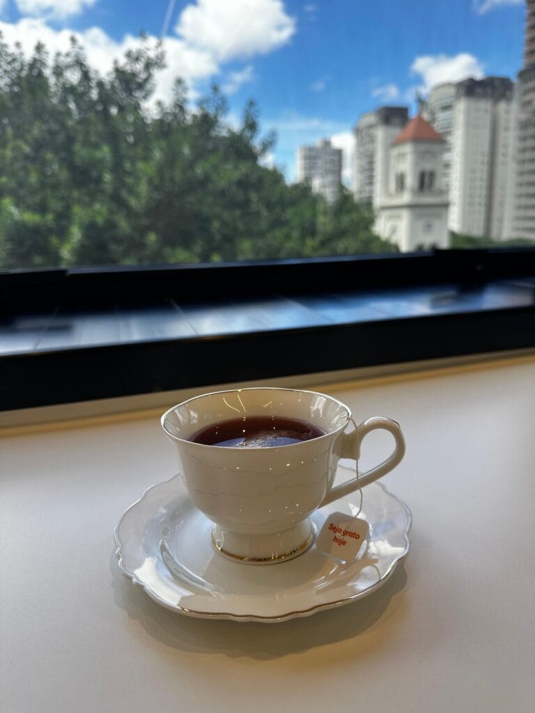 Chá servido no consultório, com vista das árvores e da igreja de Moema